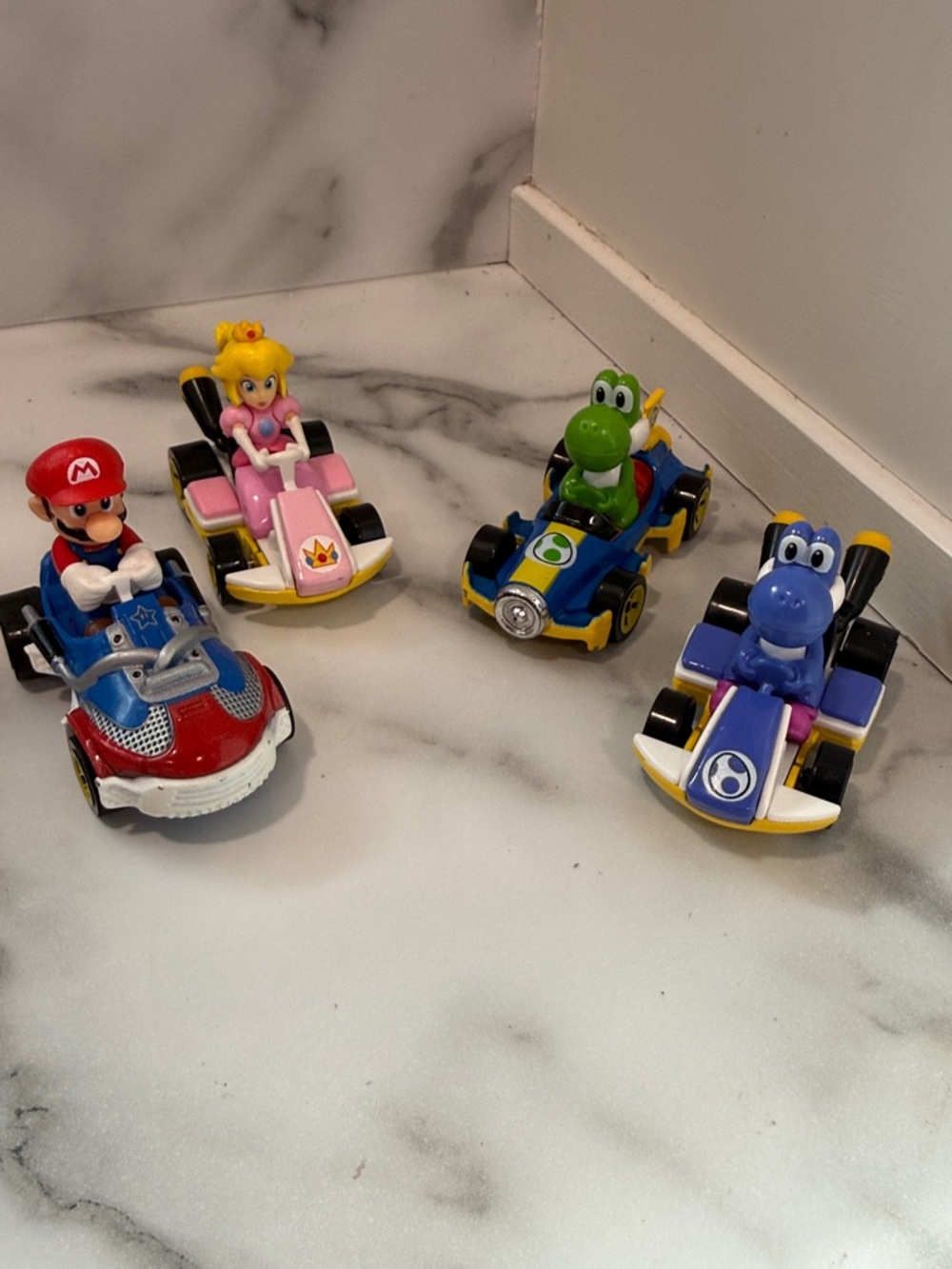 Hot Wheels Mario Kart die-cast cars featuring Mario, Princess Peach, and Yoshi